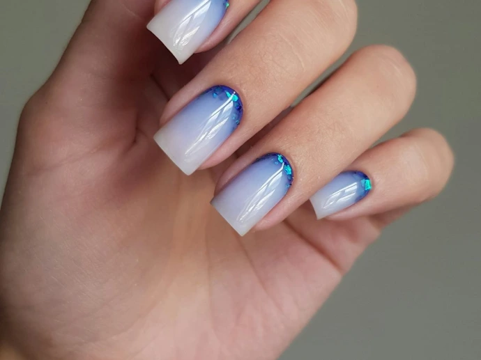 Woman's hand with blue and white ombre nails
